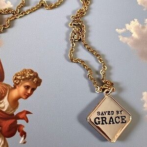 Elegant gold toned necklace featuring a 'Saved by Grace' gold plated pendant.
